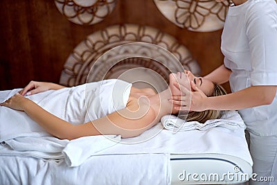 Beauty and youth. Hands of the masseuse make massage for relaxed charming woman Stock Photo