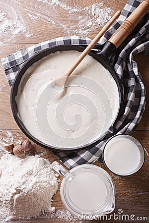 Bechamel sauce in a pan and flour, milk on the table top view Stock Photo