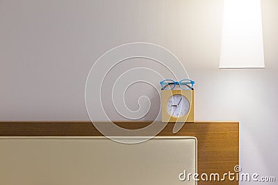 Bed headboard, eyeglasses, small clock, and over head lamp, Stock Photo