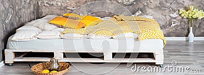 Bed made of pallets in loft interior. Stock Photo