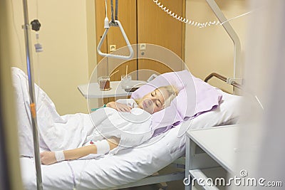 Bedridden female patient recovering after surgery in hospital care. Stock Photo