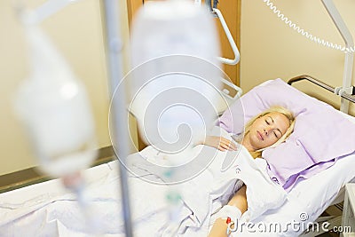 Bedridden female patient recovering after surgery in hospital care. Stock Photo