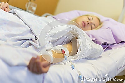 Bedridden female patient recovering after surgery in hospital care. Stock Photo