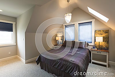 Bedroom with bed, bedside tables, vaulted ceiling, window coverings and accent lighting in contemporary upscale home interior Stock Photo