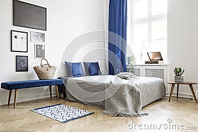 Bedroom design in modern apartment. Bed with dark blue pillows and grey duvet and blanket next to window Stock Photo