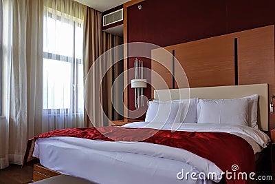 Bedroom interior. Double bed with pillows, duvet and red bedspread. Stock Photo