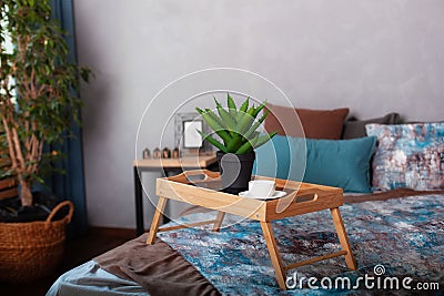 Bedroom interior with a small table on bed and a cup of coffee. Wooden breakfast tray on bed in morning. A cup of espresso in morn Stock Photo