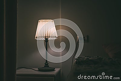 Bedroom lamp on night table in hotel room at night Stock Photo