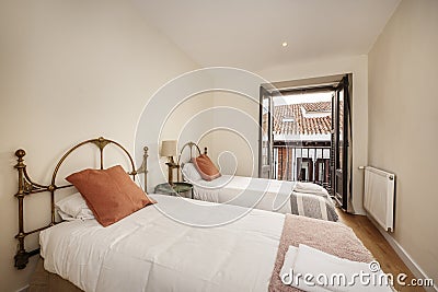 Bedroom with two single beds with brass headboards, circular wooden Stock Photo