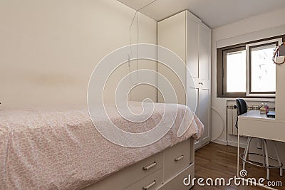 Bedroom with a youth bed with drawers next to a desk with a stool and a matching wardrobe Stock Photo