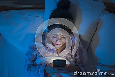 Bedtime lifestyle high angle portrait of young beautiful and happy sweet Asian Chinese girl in headband and pajamas enjoying with Stock Photo