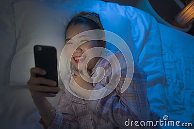 Bedtime lifestyle high angle portrait of young beautiful and happy sweet Asian Chinese woman in headband and pajamas enjoying with Stock Photo