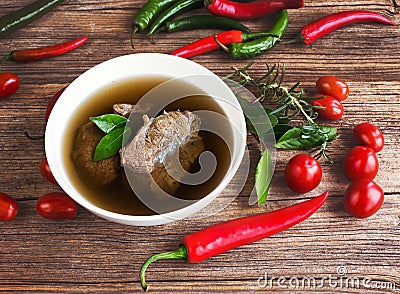 Beef broth with meat in white bowl with vegetables on wooden table Stock Photo