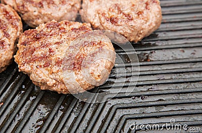 Beef burgers cooking on a griddle Stock Photo