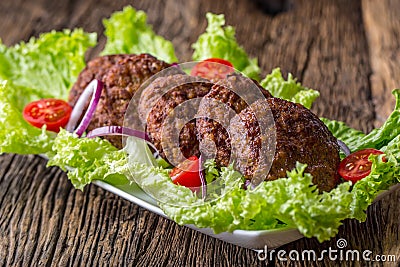 Beef Burgers meatballs cutlets with lettuce salad tomato onion on wooden board Stock Photo