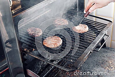 Beef Burgers And Spatula On The Hot Flaming BBQ Charcoal Grill, Close-up Stock Photo