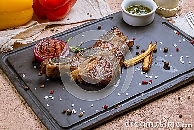 Beef ribs on bone on black stone with onion and little corn Stock Photo