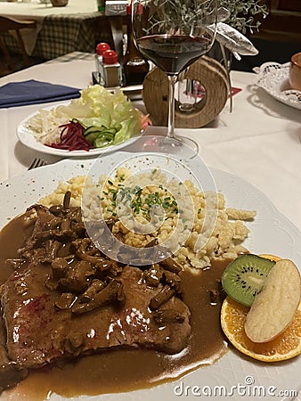 beef steak covered with gravy and chanterelle mushrooms served with spaetzle a tradional bavarian and austria pasta Stock Photo