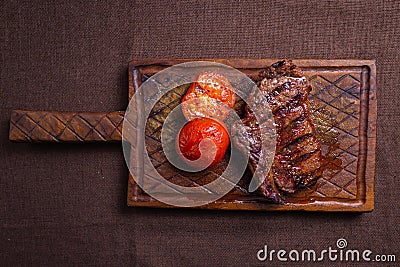 Beef steak with grilled tomatoes on a wooden board Stock Photo