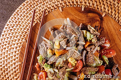 Beef stir-fry with bell peppers on wooden plate Stock Photo