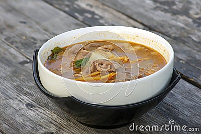 Beef Tomyam, spicy, salty, sour soup, Asian traditional food, in a white bowl on an old wooden table Stock Photo