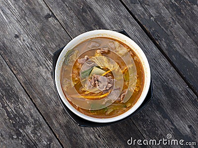 Beef Tomyam, spicy, salty, sour soup, Asian traditional food, in a white bowl on an old wooden table Stock Photo