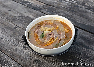 Beef Tomyam, spicy, salty, sour soup, Asian traditional food, in a white bowl on an old wooden table Stock Photo