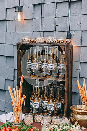 Beer and appetizing snacks. table with two mugs of lager, wooden board with grilled sausages, garlic and sauce, salted nuts. Editorial Stock Photo