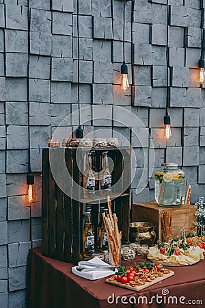 Beer and appetizing snacks. table with two mugs of lager, wooden board with grilled sausages, garlic and sauce, salted nuts. Editorial Stock Photo