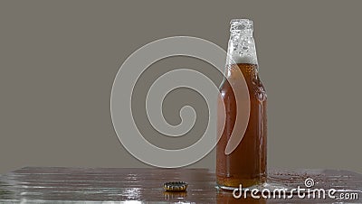 Beer bottle with openned bottlecap, foam split out on table Stock Photo