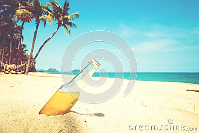 Beer bottle on a sandy beach with palm tree. Stock Photo