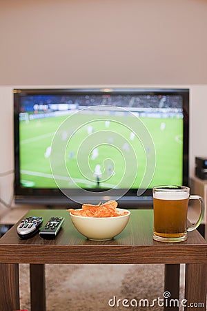 Beer, chips and remote controls on the table Stock Photo