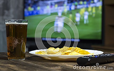 Beer, chips, TV remote control and TV in which show football game Stock Photo