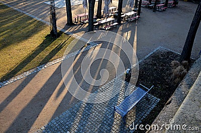 Beer front garden under the crowns of lindens. camping benches and tables with a red plastic surface. beige umbrellas park restaur Stock Photo