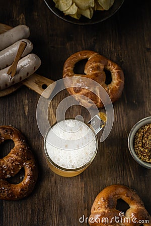 Beer glass with pretzels, bratwurst and snacks on rustic wooden table Stock Photo