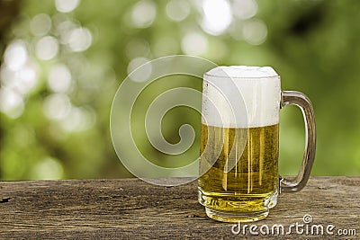 Beer in glass on wooden table with blurred green summer leaves o. Stock Photo