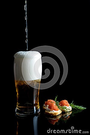 Beer poring with Caviar and bread on black background with reflections. Stock Photo