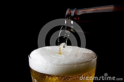 Beer is pouring into glass on black Stock Photo