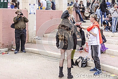 Beer-Sheva, ISRAEL - March 5, 2015: The man with the video camera shoots people in carnival costumes. Girl in black with long hair Editorial Stock Photo