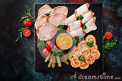 Beer snack. Meat plate with slices of bacon, slices of ham and pickles on a blue oxidized background. Stock Photo