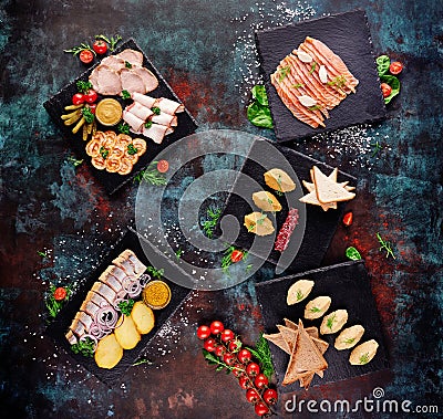 Beer snacks. Assorted meat plates with slices of bacon, ham, meat rolls and pickles on a blue oxidized background. Stock Photo