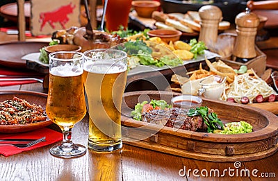 Beer table in the pub. Hot steak with sauce and vegetables. Stock Photo