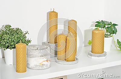 A beeswax pillar candles with traditional hex design on a shelf with various concrete and plant decor Stock Photo