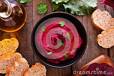 Beet hummus dip, overhead table scene with bread and ingredients on wood Stock Photo