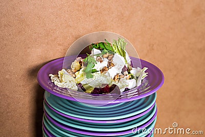 Beet salad with goat cheese, walnuts, greens and herbs and olive oil on a bright colorful ceramic plates stacked. Portion of salad Stock Photo