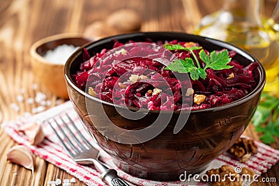 Beetroot salad with wallnuts and garlic in bowl on wooden table Stock Photo