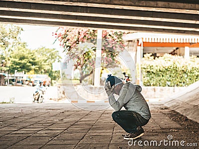 The beggars sat under the bridge with both hands holding to the head Stock Photo