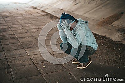 The beggars sat under the bridge with both hands holding to the head Stock Photo