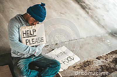 Beggars sitting under the bridge with a sign, help please Stock Photo