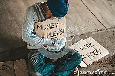 Beggars sitting under the bridge with a sign, please money Stock Photo